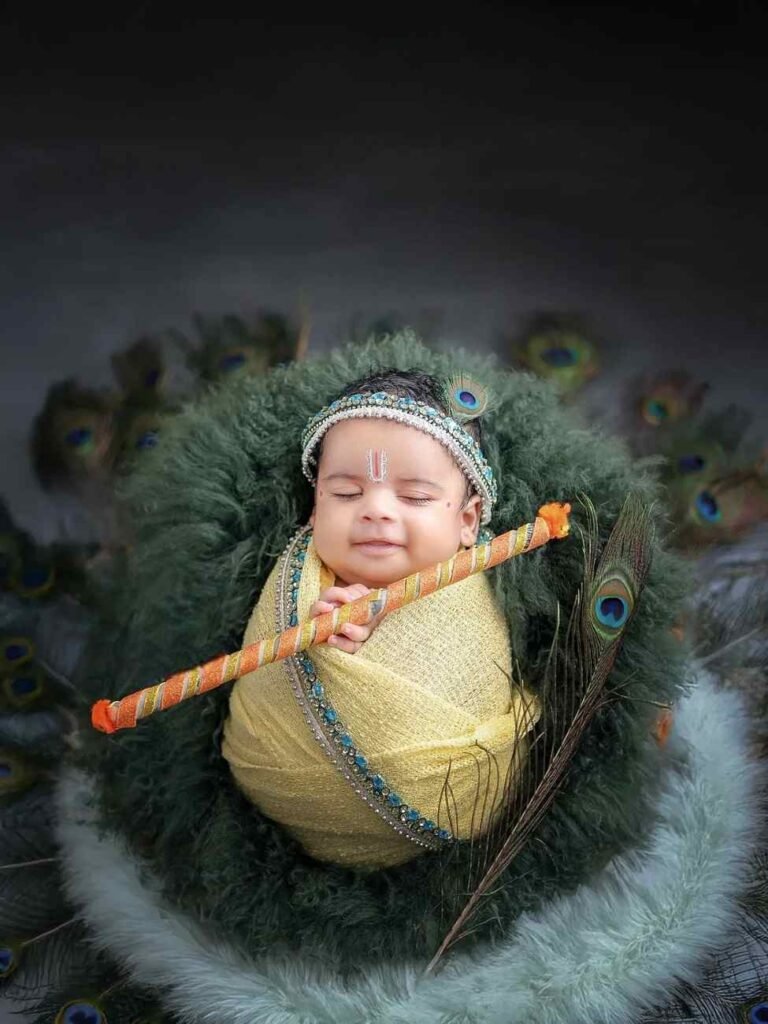 Peaceful newborn baby dressed as Bal Krishna in a yellow pitambar wrap, sleeping among peacock feathers and green fur